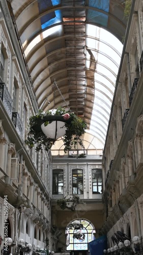 Istanbul, turkey, august 1, 2025 beautiful vaulted glass ceiling of a historical passage with ornate architecture, statues, and traditional shops flying turkish flags