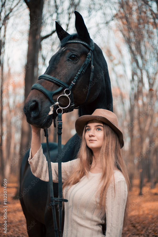 Obraz premium Woman stands with a horse in a forest during autumn while touching its face gently