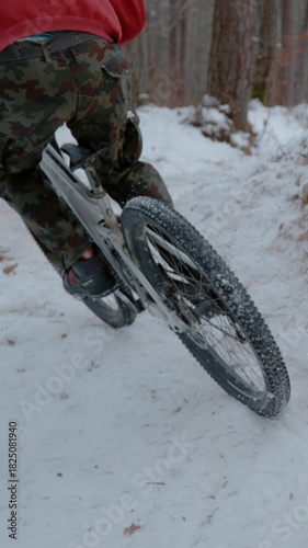SLOW MOTION: Rear view of mountain biker spraying snow at riding corner on trail. Fun bike ride in the woods after fresh snowfall. Spice of adrenaline during mountain biking in winter conditions.