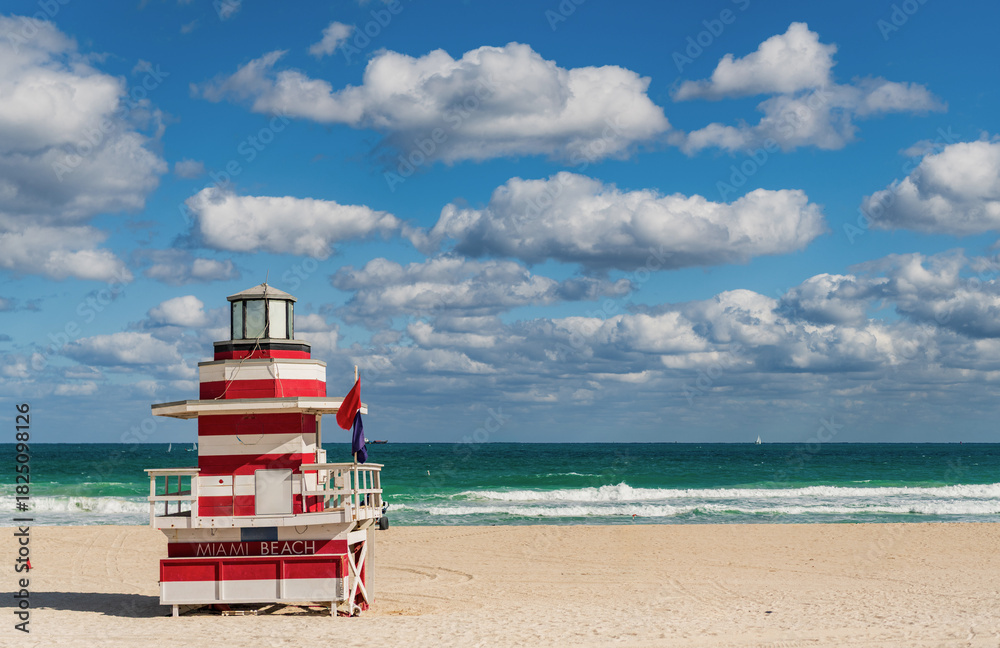 Obraz premium Lifeguard over Miami beach. Panoramic seascape of Miamis famous coastline. South Miami Beach. Miami Beach jetty. Rescue tower against the blue sky in Miami. Beautiful coastal view of Florida.