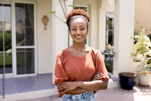 Canvas Print Happy young African American homeowner woman posing outside comfortable house