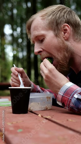 Man enjoying meal outdoors, camera zooms in on focused eating action