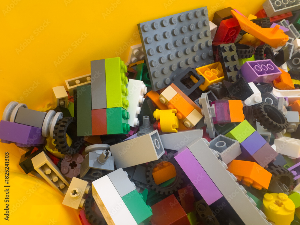 Fototapeta premium BELO HORIZONTE, MG, BRAZIL – NOVEMBER, 22, 2025: A pile of colorful LEGO building blocks and parts on a yellow background.