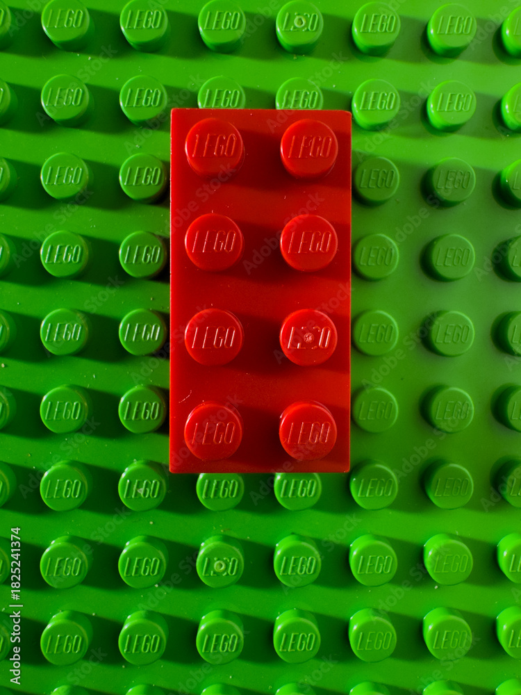 Fototapeta premium BELO HORIZONTE, MG, BRAZIL – NOVEMBER, 22, 2025: A red Lego brick centered on a green Lego baseplate.