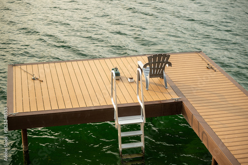 Relaxing dock at a peaceful lake with a fishing rod, chair, and a clear view of the water at sunset