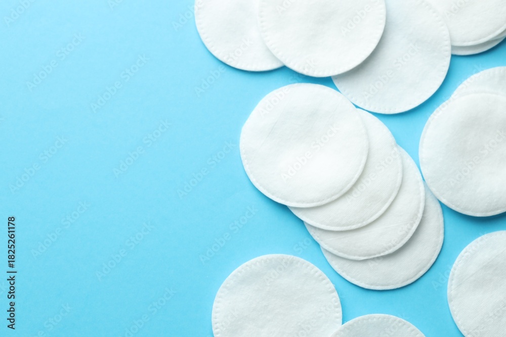Obraz premium Clean cotton pads on light blue background, flat lay. Space for text