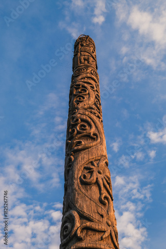Traditional Dayak Benuaq totem pole carving against blue sky