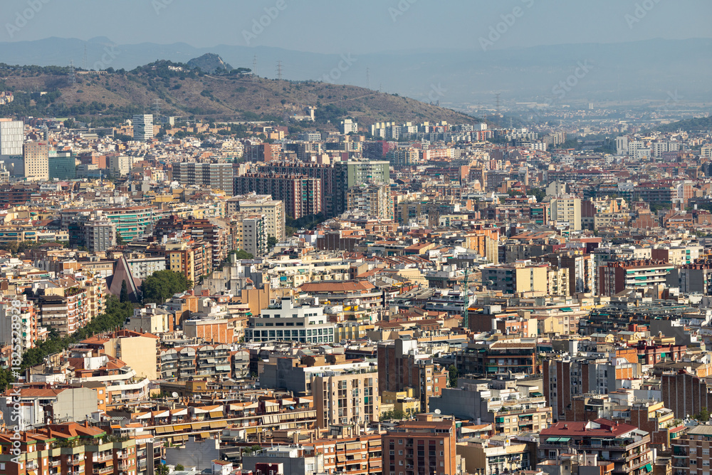 Obraz premium Urban panorama of Barcelona from Glories Tower on clear summer day, showing dense expanse of residential blocks and compact structure of city in soft daytime light