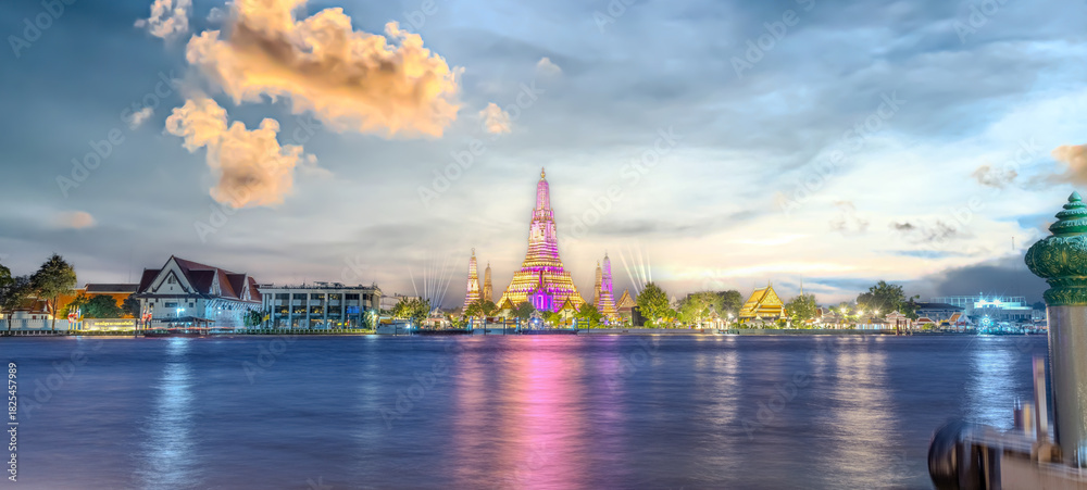 Naklejka premium 26 November 2025 Beautiful Sunset colours of Thai Temple Wat Arun on Chao Phraya River in BKK Bangkok Thailand. The magic colourful neon light display on the temple at sunset is magical.