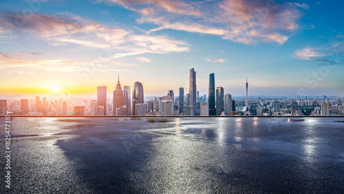 Wet asphalt road and city skyline with modern buildings at sunrise in Guangzhou