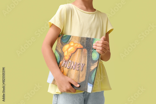 Cute little girl holding fairy tale book on green background