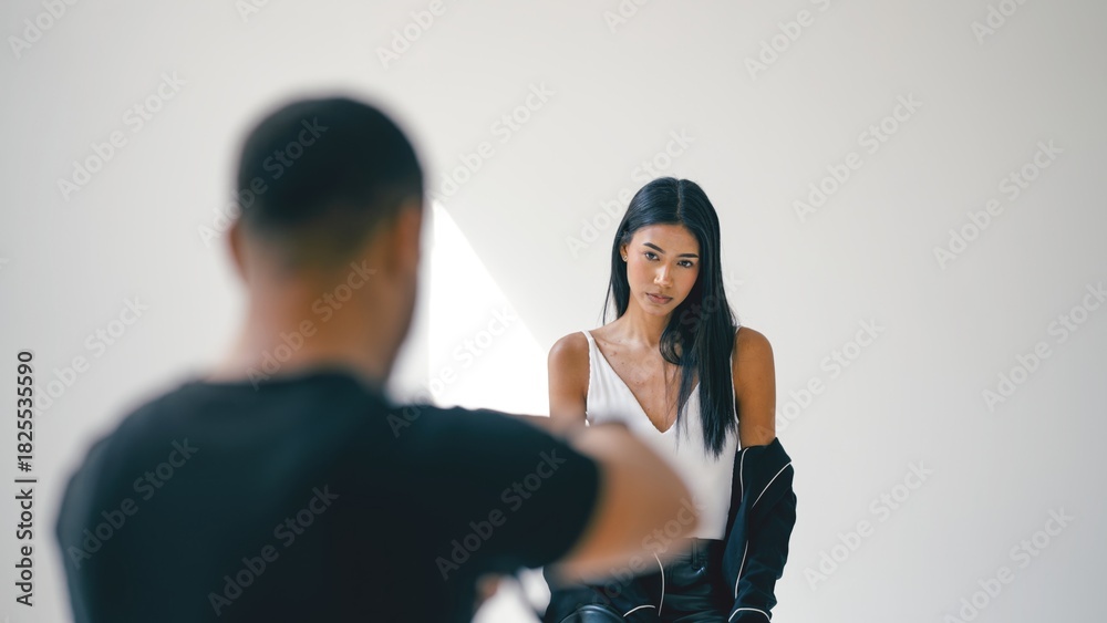 Fototapeta premium Photographer capturing stunning images of a beautiful young female model posing elegantly in a professional studio setting