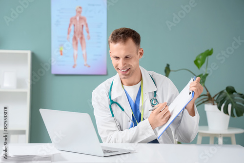 Young male doctor with lapt...