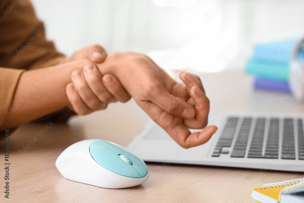 Fototapeta premium Woman suffering from pain in wrist at table in office