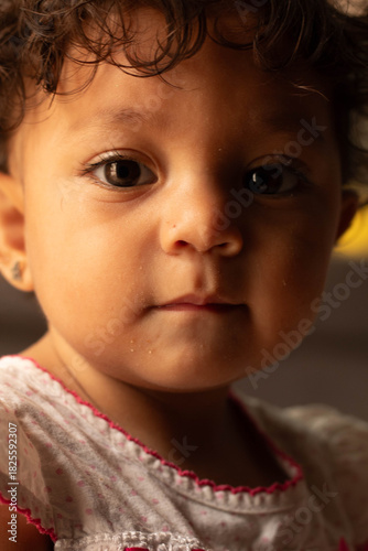 Baby girl with curly hair and expressive brown eyes