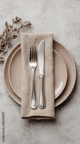 Elegant Table Setting with Beige Plate Silverware and Textured Napkin on Speckled Gray Surface Overhead View