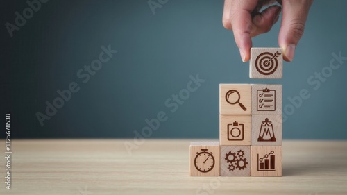 Human hand places final wooden block marked with an arrow striking a target atop a growing stack of concept icons