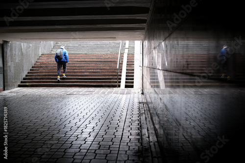 Person walks up stairs in urban tunnel after rain