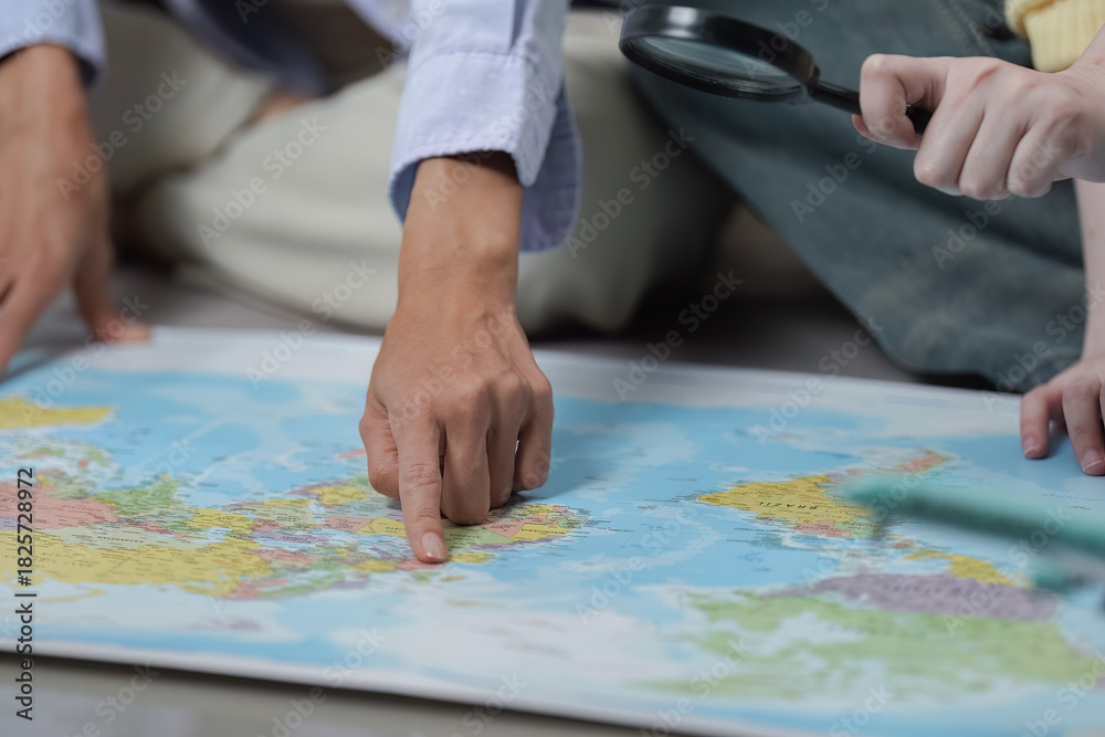 Fototapeta premium Travel Planning. Friends exploring destinations on a world map with a magnifying glass.