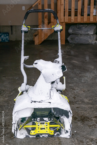 Electric Cordless Snow blower covered in Snow