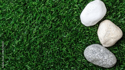 A trio of rocks in white, gray, and beige, arranged in a loose triangle on a bed of artificial grass.