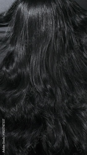 Vertical close-up of female model long black curly hair texture in slow motion
