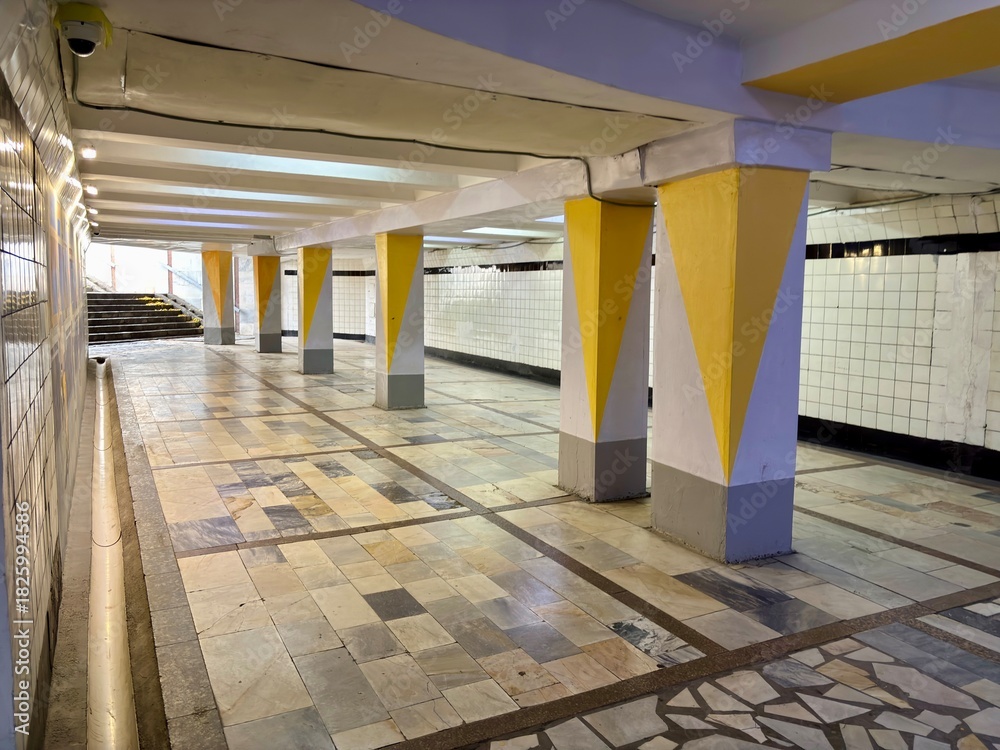 Fototapeta premium Underpass with geometric yellow columns, patterned tile floor