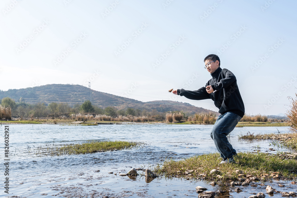 Fototapeta premium A man is practicing martial arts by the river in an open air environment, showing a dynamic stance.