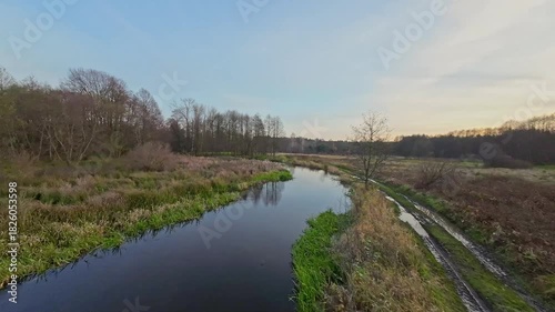 A low and fast drone flight over a river and meadow.