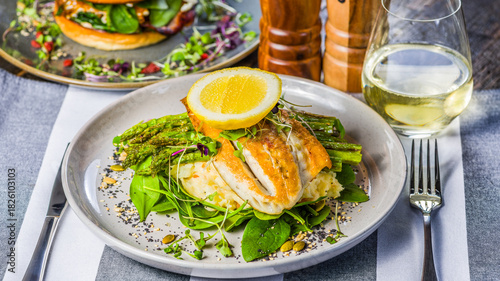 A succulent Barramundi fillet, served with tender asparagus spears and creamy mashed potato. Garnished with fresh basil leaves and finished with a slice of lemon on top.
