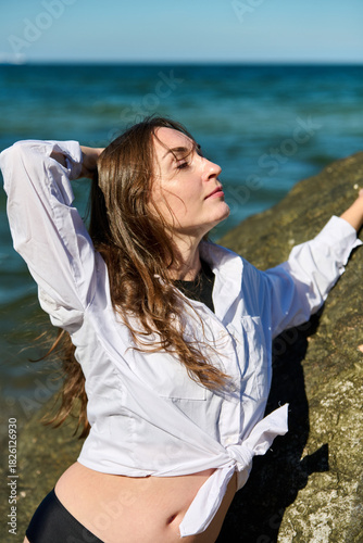 Young woman posing by Baltic Sea shore in bright daylight