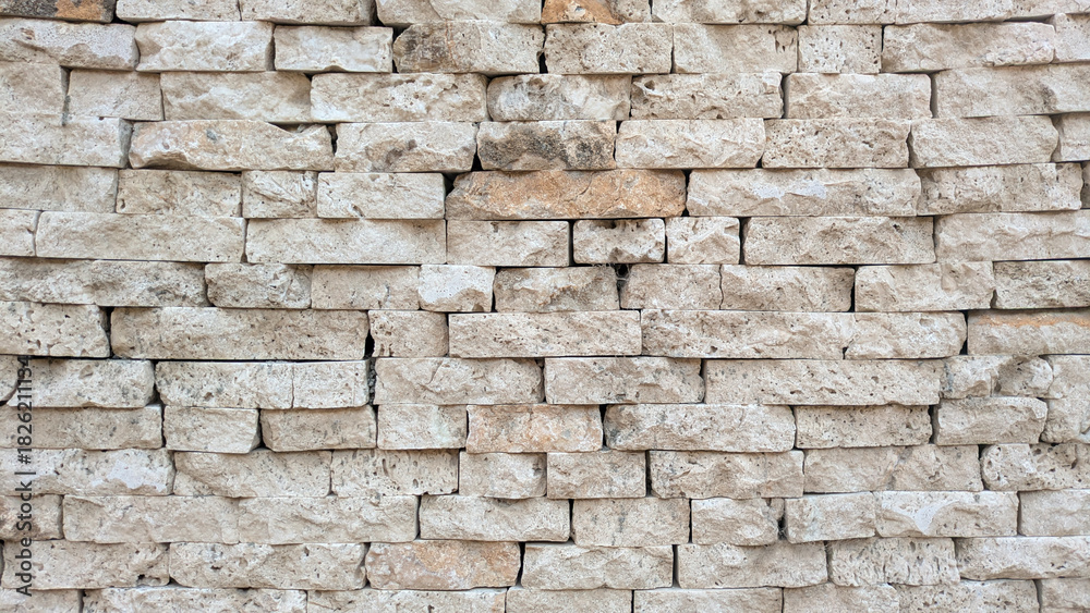 Obraz premium A close-up view of a textured stone brick wall with natural beige and cream tones, showcasing rustic architectural detail. Travertine wall