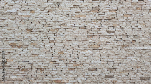 A textured stone wall with irregularly stacked beige and cream-colored stones, showcasing natural patterns and rustic charm. Travertine wall