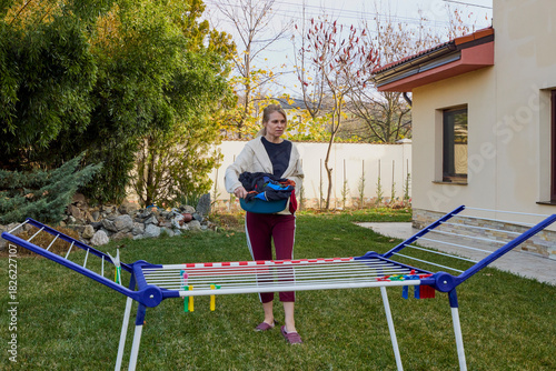 woman at home in the garden hanging laundry to dry on a dryer