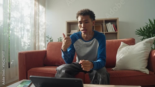 Asian teenage man learning sign language via internet with technology on tablet at home