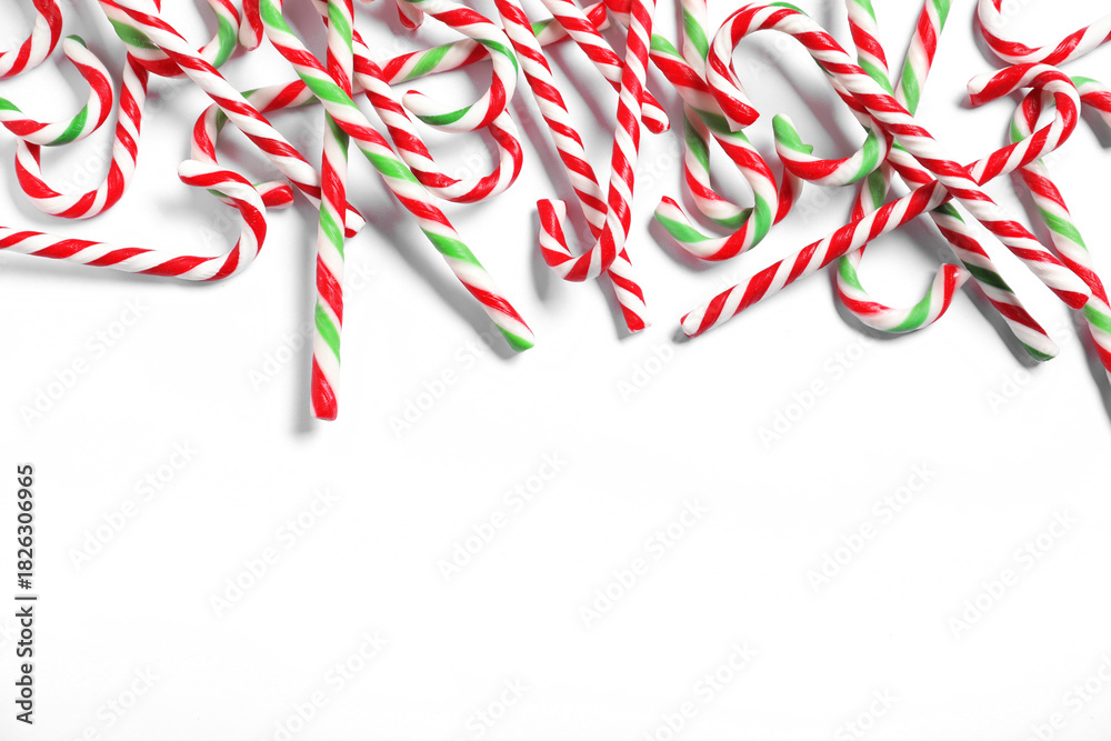 Fototapeta premium Tasty candy canes on light background, flat lay with space for text. Christmas treat