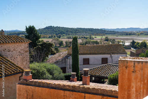 View to a medieval Spanish buildings in a village and mountains from the terrace of the villa. Luxury and calm leisure option close to Barcelona. Slow morning concept.