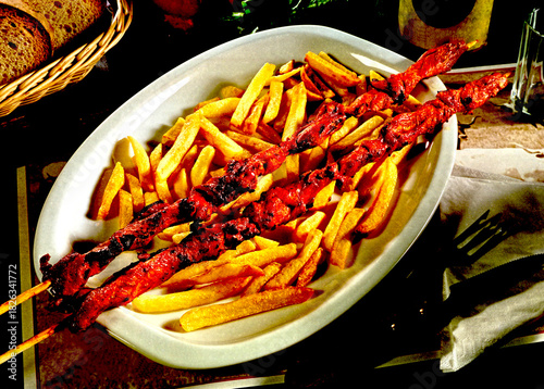 Y-95088-2 - Grilled Moroccan Lamb Kebabs with French Fries on a White Ceramic Tray .
