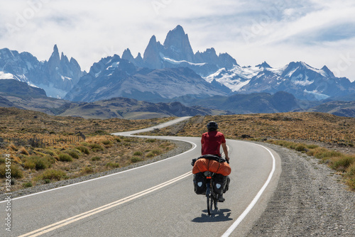 Cyclist riding winding road toward El Chalten with Fitz Roy massif, Argentina