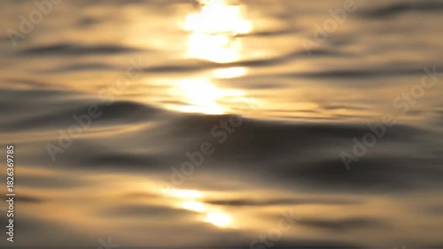 Golden sunlight reflecting on gentle water waves at sunset