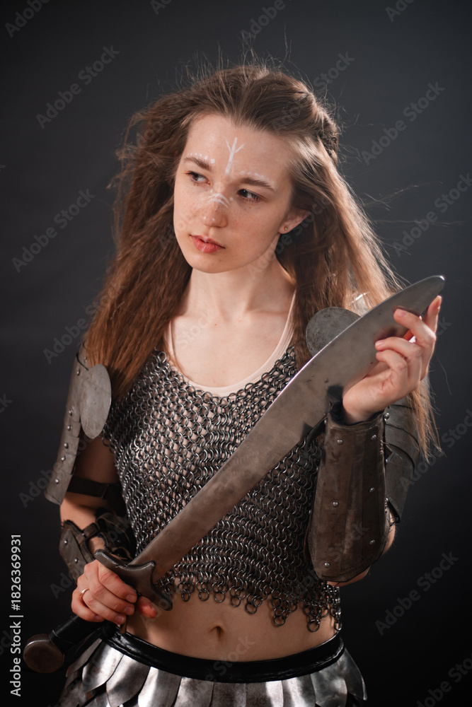 Obraz premium Portrait of a young woman, fantasy warrior in armor with a sword in her hands isolated on a dark background.