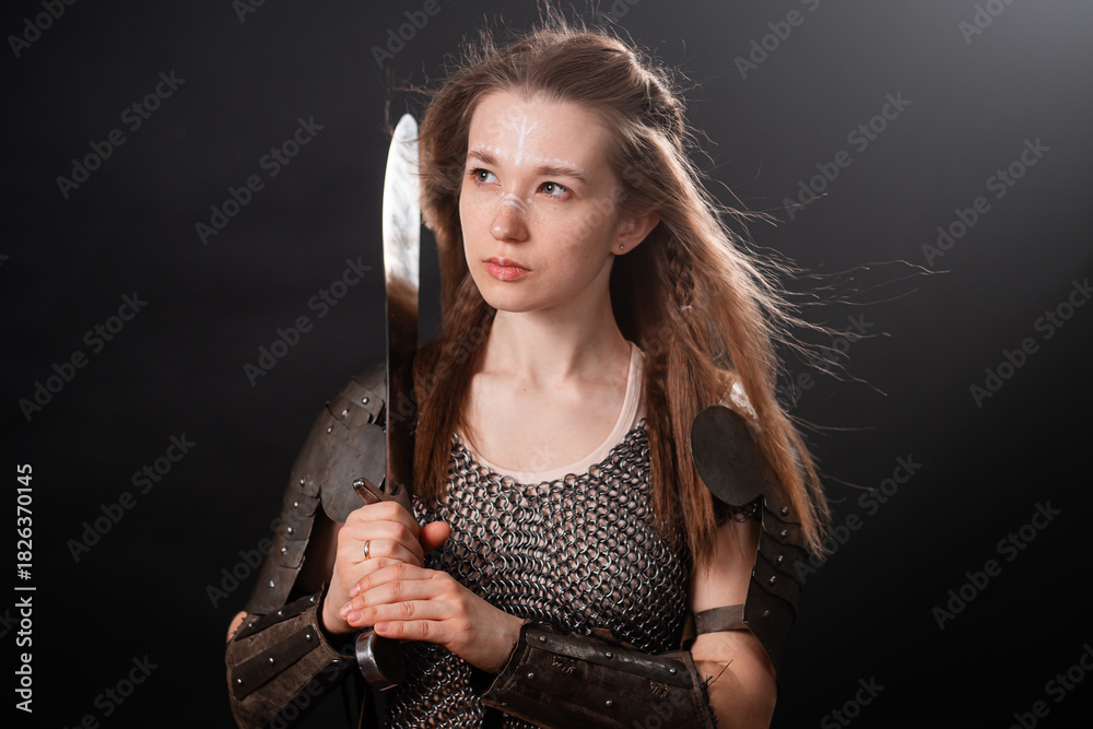 Obraz premium Portrait of a young woman, fantasy warrior in armor with a sword in her hands isolated on a dark background.