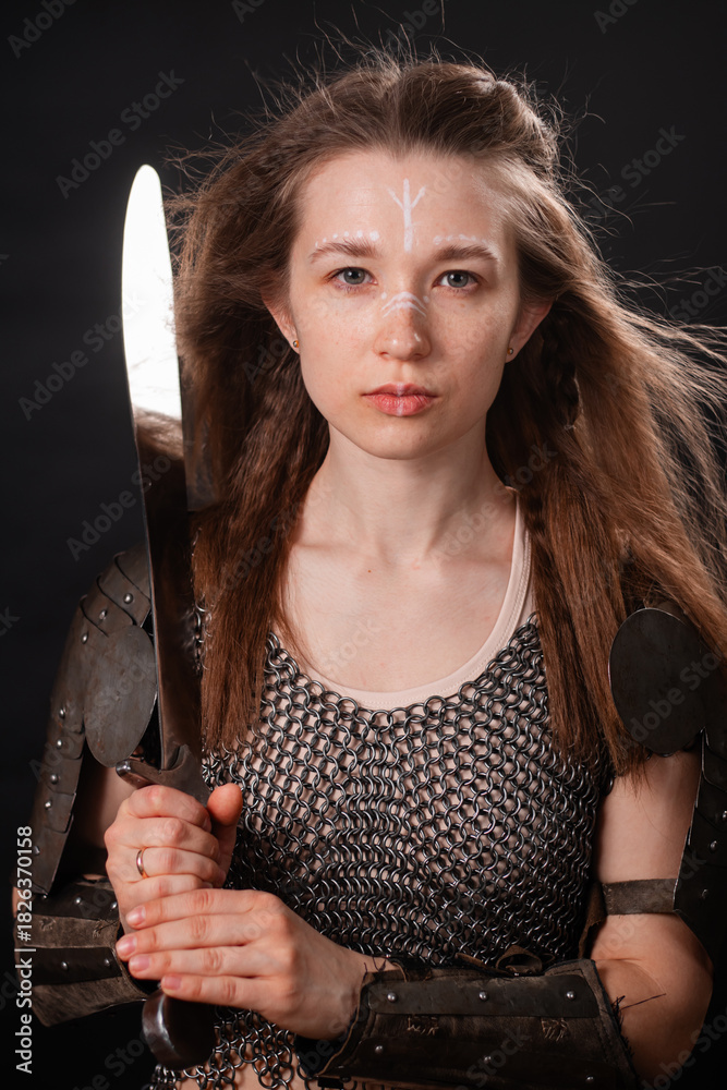 Obraz premium Portrait of a young woman, fantasy warrior in armor with a sword in her hands isolated on a dark background.
