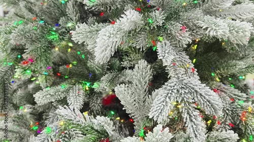 Frosty Christmas tree adorned with colorful lights in a festive winter setting