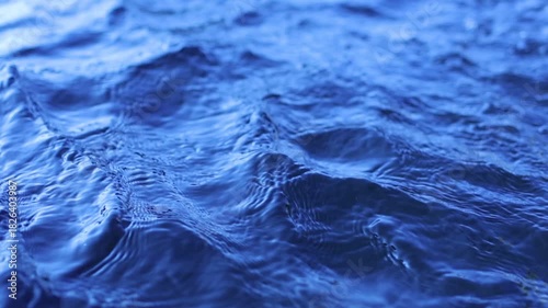 Natural background of blue water surface of sea or ocean with waves and light reflections. View of motion water swimming pool with ripples and sun glare. Unstable social issues