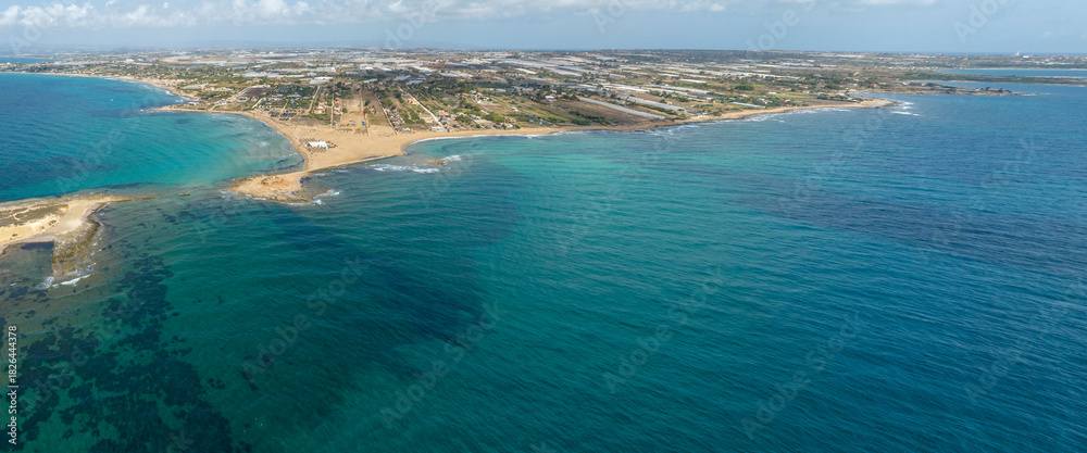Obraz premium Aerial view of the Sicilian coast. There is a long sandy beach overlooking the Mediterranean Sea. It is located in the municipality of Portopalo, in the province of Syracuse, Sicily, Italy.