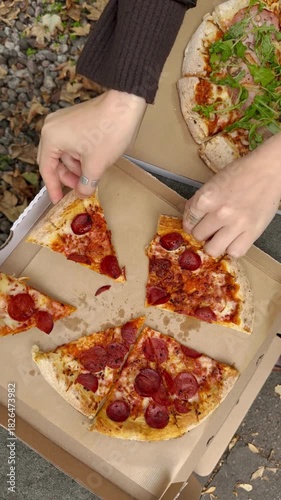 Enjoying delicious pizza with pepperoni and arugula in cardboard boxes.
