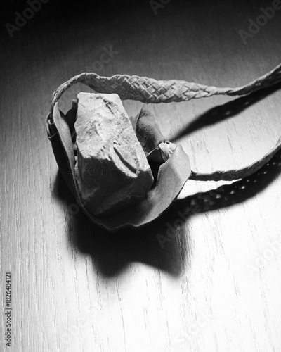 Sling with stone on wooden background