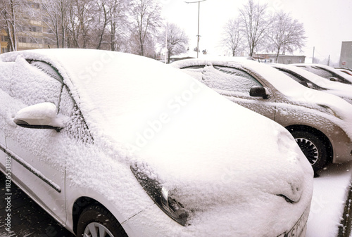 Canvas Print Cars covered in thick winter snow on a parking lot, illustrating harsh weather conditions, difficult car maintenance and the challenge of snow removal for drivers