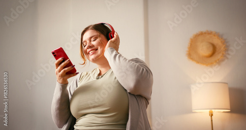 Plus size woman listens to music and dances slightly with smile